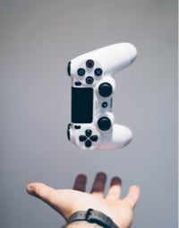 white DualShock 4 controller hovering above a hand